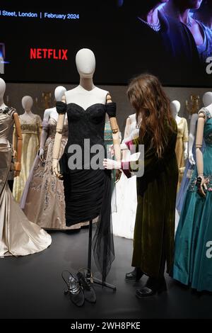 Photo du dossier datée du 9/1/2024 d'un assistant de galerie ajuste une reproduction de la robe vengeante de la princesse Diana, qui fait partie de la collection de plus de 450 costumes, décors et accessoires de la série Netflix The Crown, exposée à Bonhams dans le centre de Londres, avant la vente aux enchères. Les accessoires de la série télévisée The Crown, y compris le Queen's Gold State Coach, se sont vendus aux enchères pour plus de 1,67 millions de livres sterling. Date d'émission : jeudi 8 février 2024. Banque D'Images