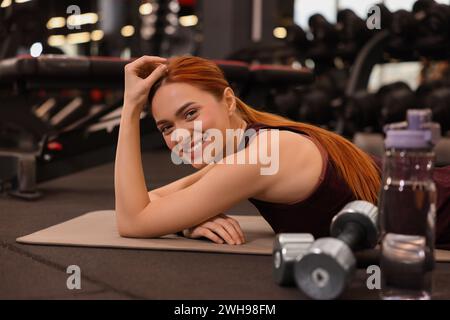 Heureuse jeune femme allongée sur le tapis dans la salle de gym Banque D'Images