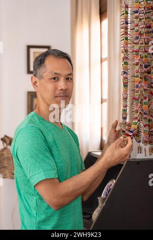 Homme japonais tenant une grue en papier regardant la caméra. Souvenirs dans la maison familiale Banque D'Images