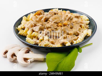 pâtes à la viande et sauce aux champignons sur une assiette sur fond blanc Banque D'Images