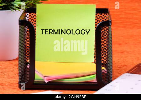 Texte TERMINOLOGIQUE écrit sur un autocollant vert à côté des fournitures de bureau sur fond orange Banque D'Images