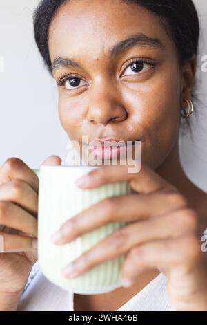 Jeune femme biraciale aime boire une boisson chaude à la maison Banque D'Images