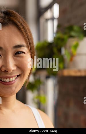Femme asiatique sourit chaleureusement dans un environnement de bureau d'affaires décontracté avec espace de copie Banque D'Images