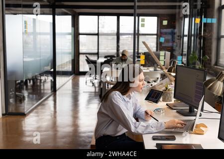 Jeune femme caucasienne travaille avec diligence dans un bureau d'affaires moderne et décontracté Banque D'Images