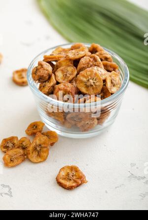 Tranches de bananes biologiques fraîches séchées dans un bol en verre avec feuille verte.Macro Banque D'Images