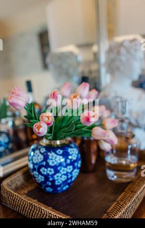 Fausses tulipes en vase bleu sur plateau en rotin marron Banque D'Images