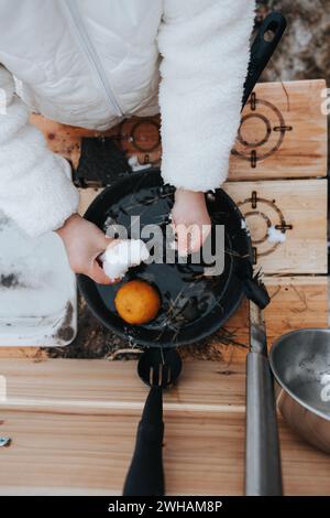 Fille créative avec de la neige dans la cuisine de boue extérieure Banque D'Images