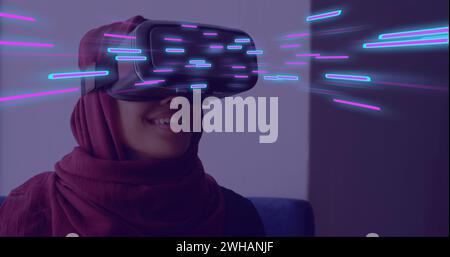 Image de traînées lumineuses incandescentes de transfert de données sur une femme biraciale dans un casque vr Banque D'Images