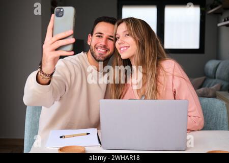 Espagnol couple heureux prenant un selfie ensemble à la maison. Banque D'Images