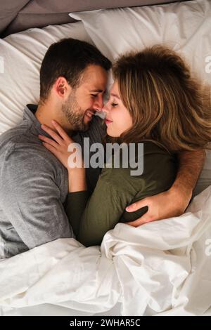 Vue de dessus d'un couple espagnol serrant amoureux dans un lit. Banque D'Images