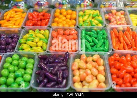 Un assortiment de haricots mung en forme de fruits, des desserts thaïlandais vibrants, conçus pour ressembler à des fruits et légumes miniatures, présentés dans des récipients transparents à Banque D'Images