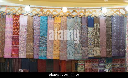 Textiles traditionnels colorés avec des motifs complexes accrochés sur un marché, mettant en valeur la beauté culturelle de l'artisanat du tissu Banque D'Images