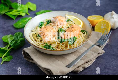 Cuisine italienne : spaghetti au saumon, crème et épinards gros plan sur l'assiette sur la table. horizontal Banque D'Images