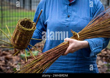 Artisan tient une maison d'oiseaux tissée et une gerbe de branches de saule, tissant le panier de saule Banque D'Images