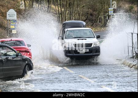 Major's Green, Bromsgrove, 9 février 2024. Trois femmes se sont retrouvées bloquées alors qu'elles essayaient de naviguer dans les inondations dans les Midlands. Les femmes ont finalement trouvé leur chemin hors d'une banque sur Peterbrook Road dans Major's Green et le long de balustrades métalliques comme de nombreux conducteurs passaient, provoquant d'énormes vagues d'arc en raison de fortes précipitations la nuit et tout au long de la journée. Crédit : arrêtez Press Media/Alamy Live News Banque D'Images