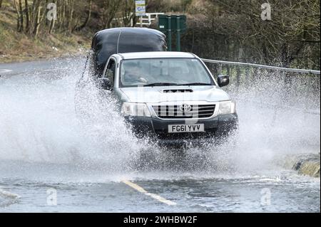 Major's Green, Bromsgrove, 9 février 2024. Trois femmes se sont retrouvées bloquées alors qu'elles essayaient de naviguer dans les inondations dans les Midlands. Les femmes ont finalement trouvé leur chemin hors d'une banque sur Peterbrook Road dans Major's Green et le long de balustrades métalliques comme de nombreux conducteurs passaient, provoquant d'énormes vagues d'arc en raison de fortes précipitations la nuit et tout au long de la journée. Crédit : arrêtez Press Media/Alamy Live News Banque D'Images