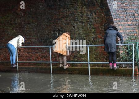 Major's Green, Bromsgrove, 9 février 2024. Trois femmes se sont retrouvées bloquées alors qu'elles essayaient de naviguer dans les inondations dans les Midlands. Les femmes ont finalement trouvé leur chemin hors d'une banque sur Peterbrook Road dans Major's Green et le long de balustrades métalliques comme de nombreux conducteurs passaient, provoquant d'énormes vagues d'arc en raison de fortes précipitations la nuit et tout au long de la journée. Crédit : arrêtez Press Media/Alamy Live News Banque D'Images