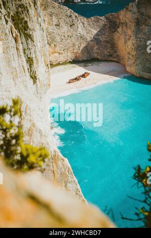 Plan vertical du naufrage sur la plage de Navagio avec de l'eau de mer bleu turquoise entourée d'énormes falaises blanches. Emplacement célèbre de point de repère sur l'île de Zakynthos, Grèce. Couleurs chaudes Banque D'Images
