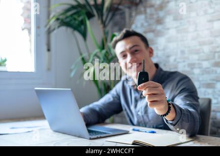 Portrait gros plan de la main d'un jeune homme beau et attrayant montrant et tenant les clés de la voiture à la caméra, emmenant au client achetant un nouveau véhicule. Vendeur travaillant sur les affaires Banque D'Images