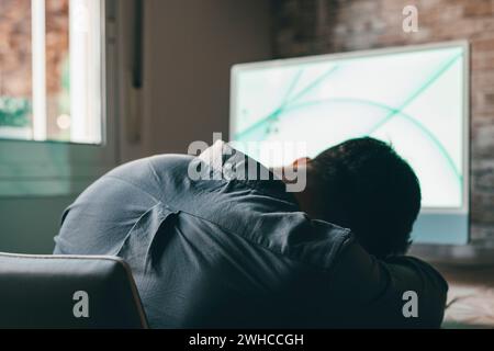 Épuisé jeune employé masculin caucasien bureau dormir bureau surmenage préparant le rapport. Un homme fatigué s'endormit sur le lieu de travail, travaille tard pour respecter la date limite. Fatigue, concept d'épuisement. Banque D'Images