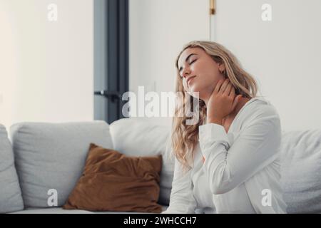 Fermer femme fatiguée massant les muscles du cou après un long travail sédentaire, fille épuisée ressentant un malaise, malaise et malsain, souffrant de tension ou de spasme, concept de problème de santé Banque D'Images