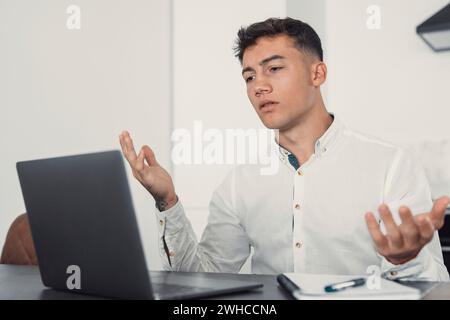 Malheureux jeune travailleur caucasien masculin dans les lunettes regarder l'écran d'ordinateur portable choqué par la panne de gadget ou des problèmes opérationnels. Homme frustré confus surpris par une erreur inattendue sur le périphérique informatique. Banque D'Images