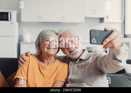 Heureux vieux couple prenant selfie sur téléphone portable, souriant époux matures aînés épouse d'âge moyen et mari retraité riant tenant le téléphone faire l'autoportrait sur l'appareil photo de smartphone, se concentrer sur l'affichage mobile Banque D'Images