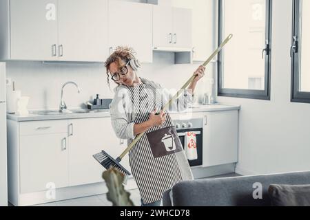 Insouciante jeune femme heureuse nettoyage maison salon amusez-vous à danser avec vadrouille, souriante fille millénaire ravie se sentir excitée profiter de faire maison chor Banque D'Images