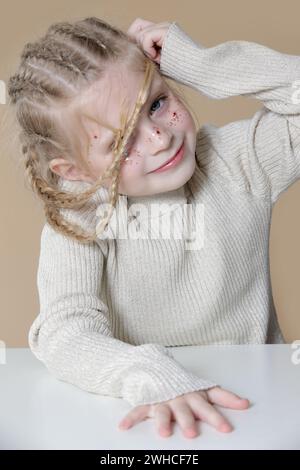 Portrait de petite fille blonde mignonne avec des tresses de boxeur et des paillettes om visage Banque D'Images