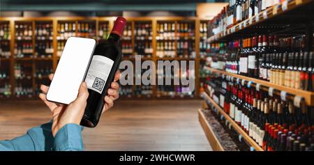 Personne utilisant le téléphone intelligent pour scanner e-étiquette sur la bouteille de vin dans le magasin d'alcool. Banque D'Images