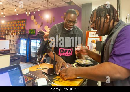 Detroit, Michigan, États-Unis. 8 février 2024. Le gouverneur Garlin Gilchrist, du Michigan, a passé une heure en tant que serveur au restaurant Yum Village pour promouvoir la campagne pour un juste salaire. One Fair Wage fonctionne pour un salaire minimum vital pour tous et l'élimination du salaire inférieur au salaire minimum pour les travailleurs pourvus de pourboires. Gilchrist (à gauche) passe en revue les commandes des convives avec Godwin Ihentuge, fondateur de Yum Village. Crédit : Jim West/Alamy Live News Banque D'Images