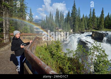 Femme aux chutes Athabasca avec arc-en-ciel, rivière Athabasca, promenade des champs de glace, parc national Jasper, Alberta, Canada Banque D'Images