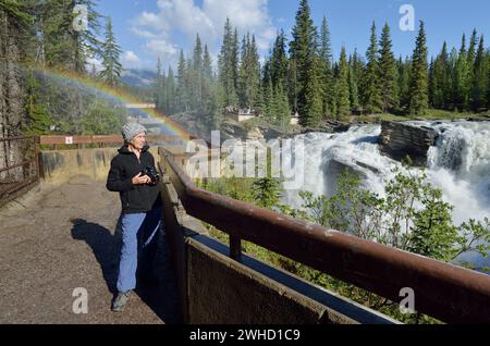 Femme aux chutes Athabasca avec arc-en-ciel, rivière Athabasca, promenade des champs de glace, parc national Jasper, Alberta, Canada Banque D'Images