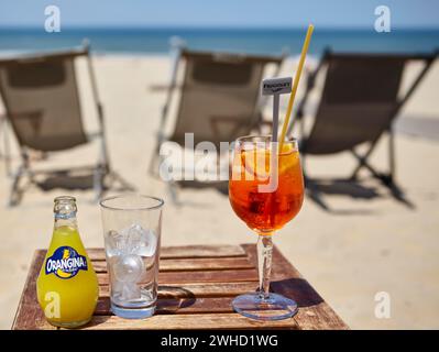 Une bouteille d'Orangina, un verre avec des glaçons et un verre d'Aperol Spritz avec une paille dans un bar de plage à Soulac-sur-mer, Gironde Banque D'Images