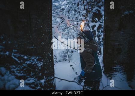 Le petit garçon fait une randonnée aux flambeaux à travers la forêt locale Banque D'Images