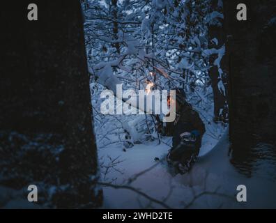 Le petit garçon fait une randonnée aux flambeaux à travers la forêt locale Banque D'Images