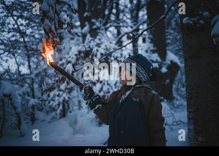 Le petit garçon fait une randonnée aux flambeaux à travers la forêt locale Banque D'Images