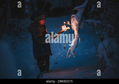 Le petit garçon fait une randonnée aux flambeaux à travers la forêt locale Banque D'Images