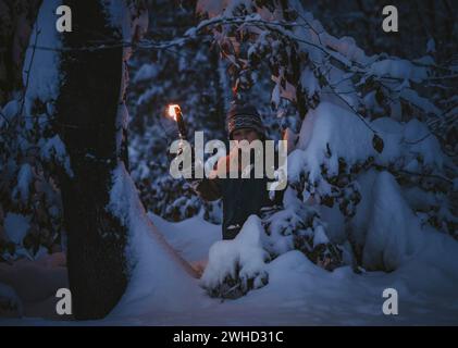 Le petit garçon fait une randonnée aux flambeaux à travers la forêt locale Banque D'Images