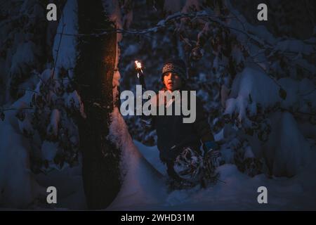 Le petit garçon fait une randonnée aux flambeaux à travers la forêt locale Banque D'Images