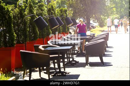 café de rue, tables et tabourets dans la rue. restaurant, cafétéria. La fille le serveur à de petites tables dans la rue. Cafés dans la rue, dans le Banque D'Images