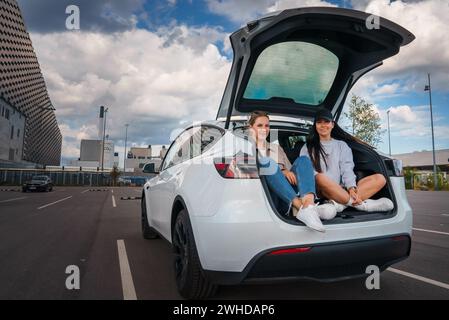 Deux amis se relaxant dans le coffre de voiture électrique, Urban Denmark ou Suède Banque D'Images