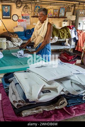 Un homme repasse des chemises avec un fer antique à Dhobi Khana public Laundry, Fort Kochi, Cochin, Kerala, Inde Banque D'Images