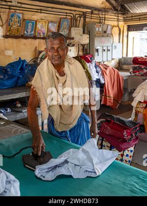 Un homme repasse des chemises avec un fer antique à Dhobi Khana public Laundry, Fort Kochi, Cochin, Kerala, Inde Banque D'Images