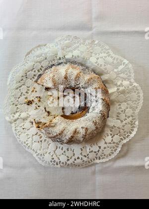 Le gâteau rond de marbre avec du sucre blanc en poudre est coupé sur le côté gauche et un quart du gâteau est absent de l'assiette Banque D'Images