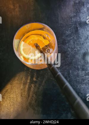Une boisson d'été orange avec de l'alcool dans un verre avec une paille noire et une tranche de citron dans le restaurant Banque D'Images
