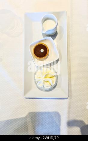 Un décor avec tartelettes au chocolat et crème et un pichet de lait pour le dessert sur une assiette en porcelaine blanche Banque D'Images