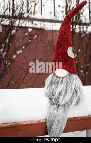 Nain avec symbole de coeur sur le banc dans la neige. Cadeau romantique. Concept de la Saint-Valentin. GNOME avec coeur et chapeau rouge dans la neige. Fond d'amour. Banque D'Images