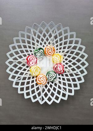 Huit sucettes sont encore enveloppées dans une feuille de plastique dans un cercle sur un bol blanc Banque D'Images