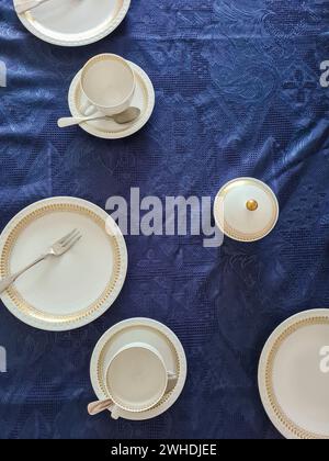 Service de gâteau en porcelaine fine avec bordure dorée sur une nappe festive bleue Banque D'Images